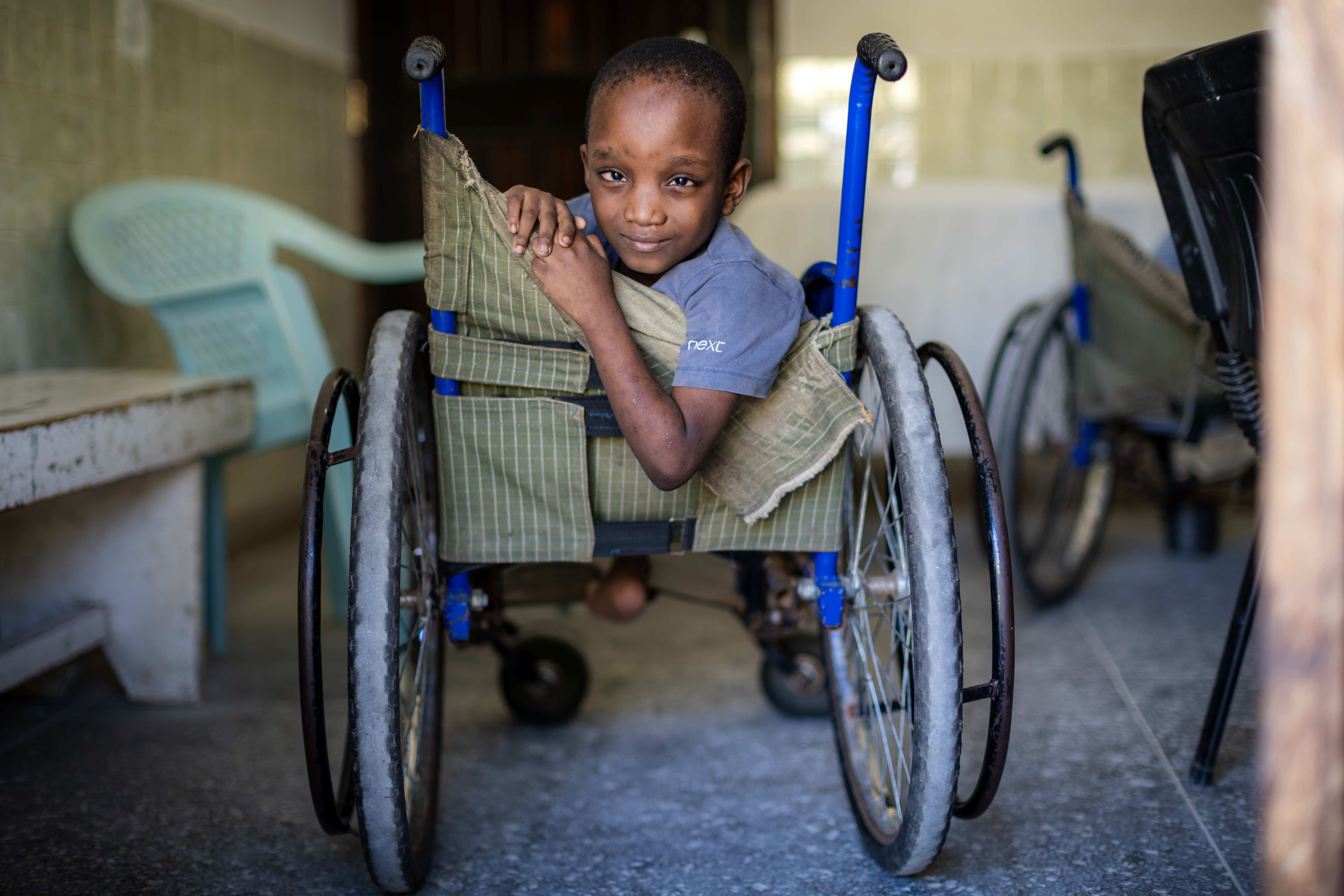 Ein Junge aus Kenia sitzt im Rollstuhl und befindet sich in einer Klinik in Mombasa. Er lächelt in die Kamera. (Quelle: Lars Heidrich)