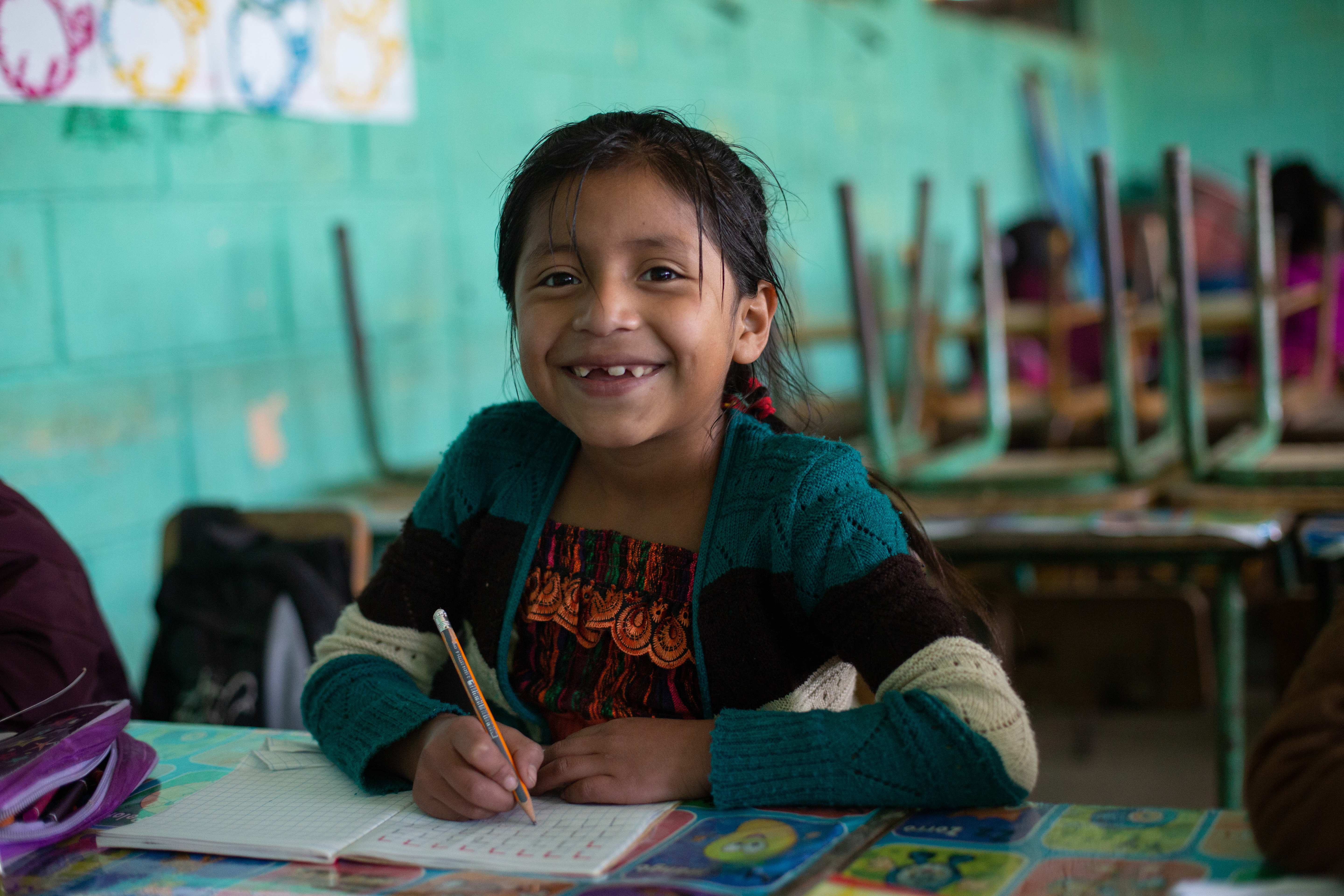 Eine Schulklasse in Guatemala. Mädchen aus der ersten Reihe lächelt in die Kamera. (Quelle: Jakob Studnar)