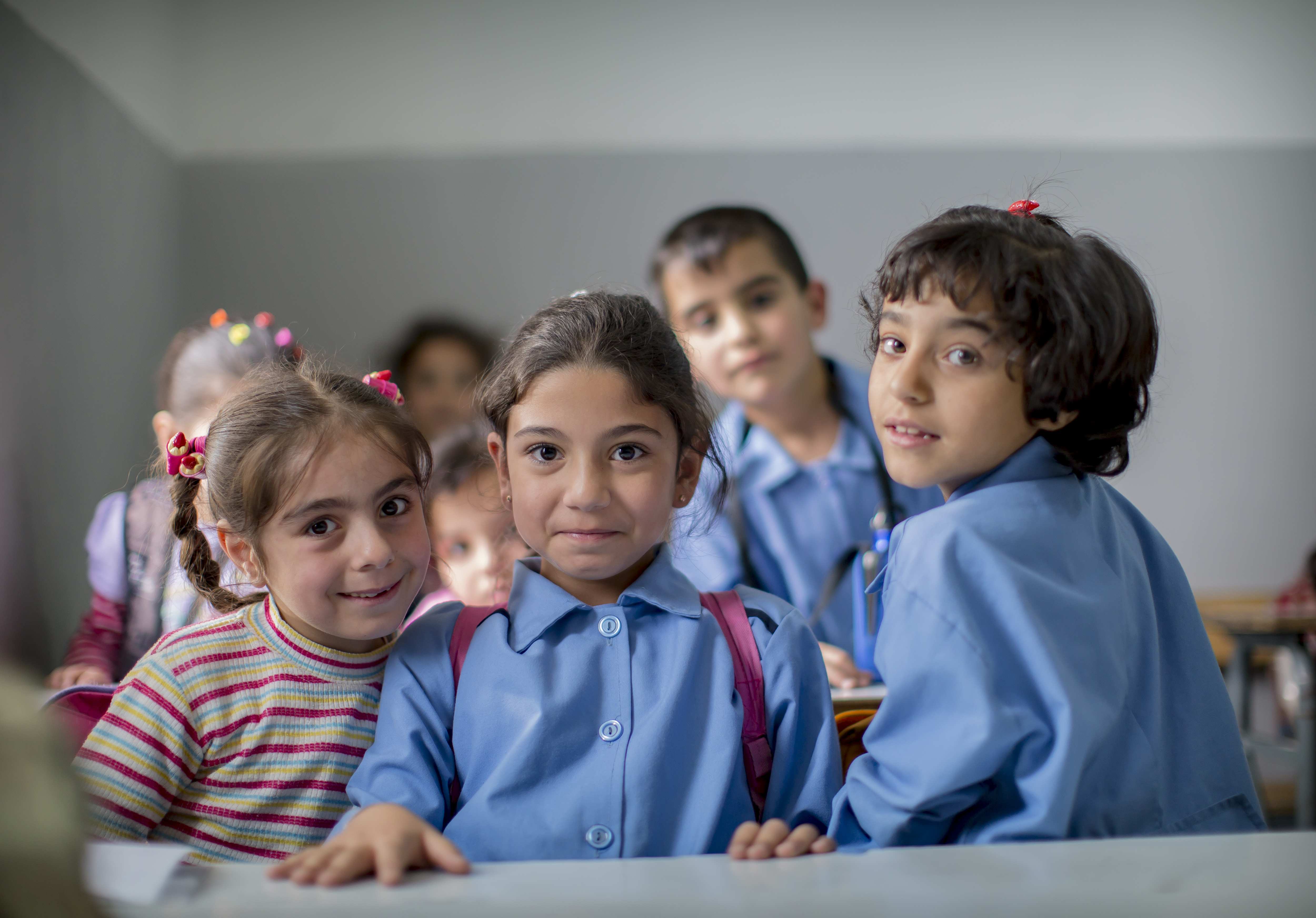 Besuch von Flüchtlingskindern in einer Schule. Kinder lächeln in die Kamera (Quelle: Jakob Studnar)