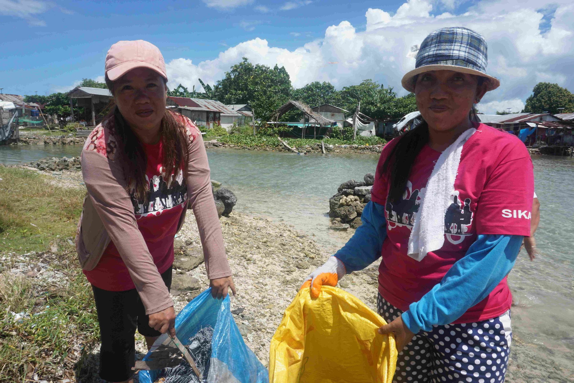 Zwei Frauen aus einer Selbsthilfegruppen auf den Philippinen sammeln Müll am Strand ein. (Quelle: Ludwig Grunewald)